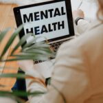 A woman focuses on mental health resources through her laptop in a home office setting.